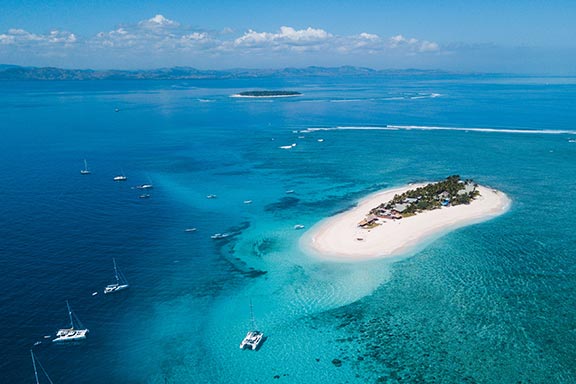 aerial-image-of-namotu-island-surrounded-by-boats-and-reef-with-beautiful-water