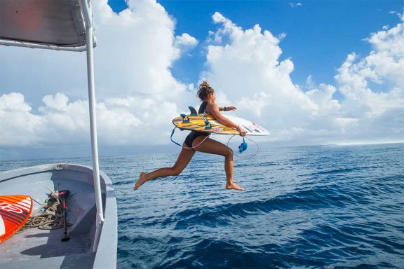 girl-jumping-into-water-off-boat-for-surfing-break-near-namotu-island